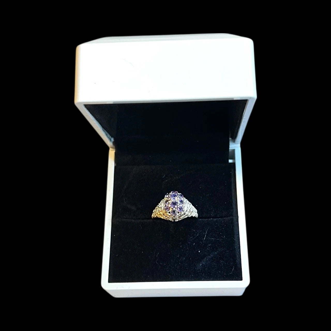 Gold ring with a purple amethyst gemstone in a white box on a black background
