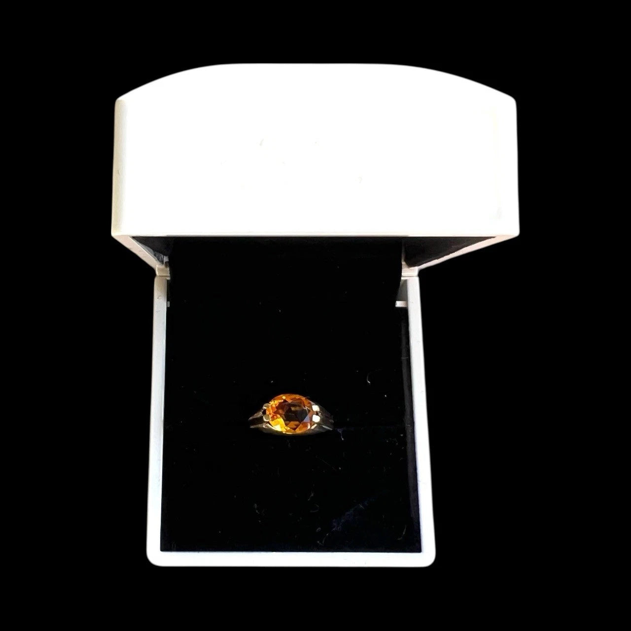 Ring with a large orange citrine gemstone in a white box on a black background