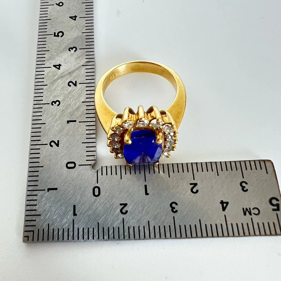 Gold ring with a blue tanzanite gemstone and diamonds next to a ruler on a white background