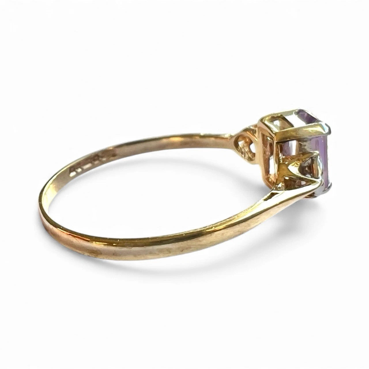 Three stone gold ring with a amethyst gemstone and diamonds on a white background
