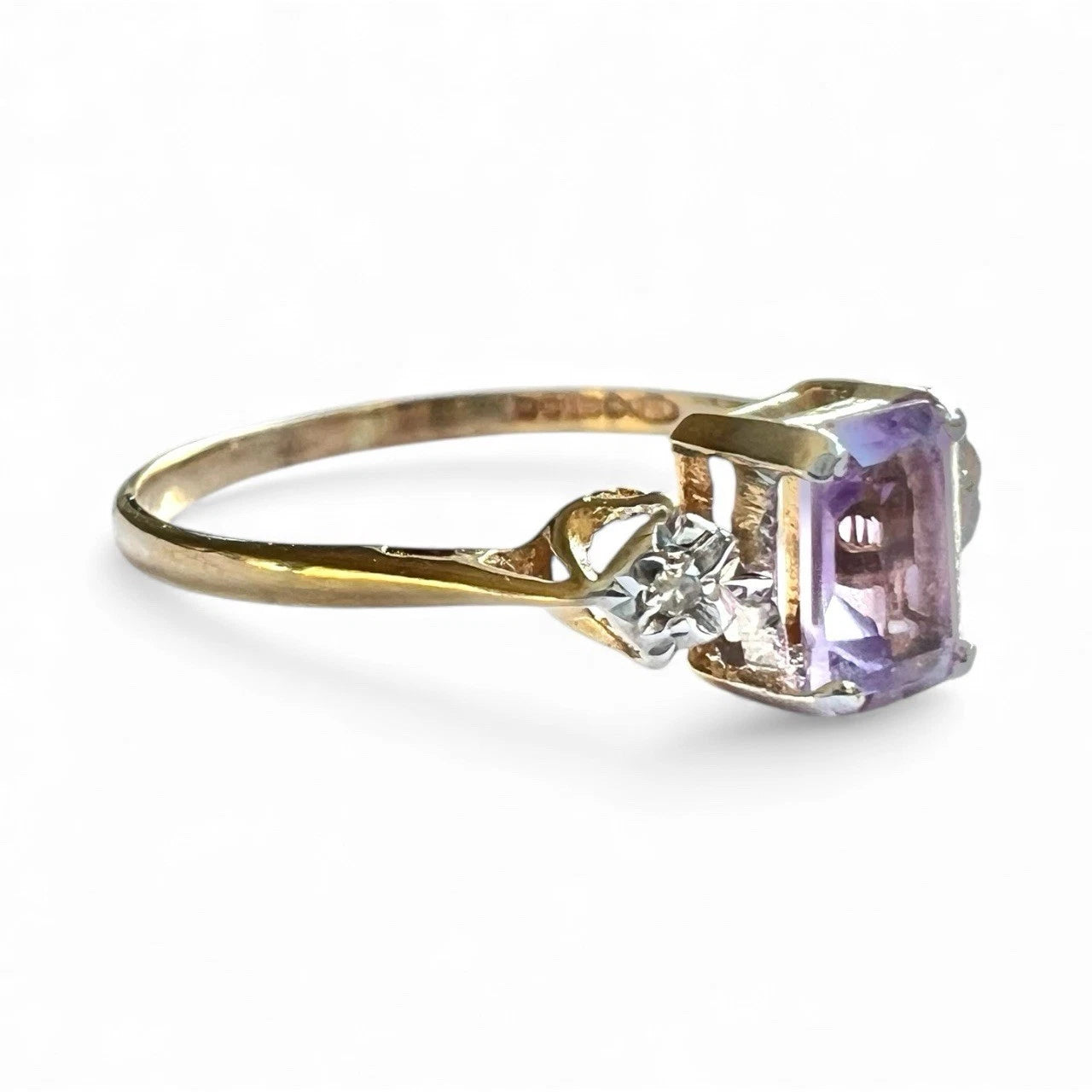 Gold ring with a purple gemstone and diamond on a white background
