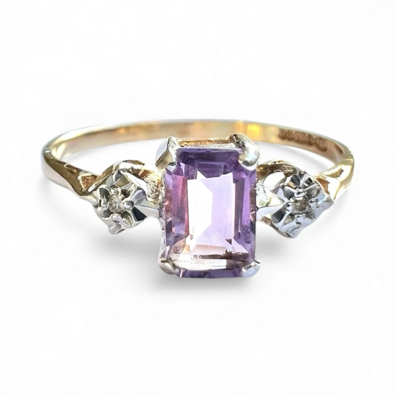Gold ring with a purple amethyst gemstone and two smaller diamonds on a white background