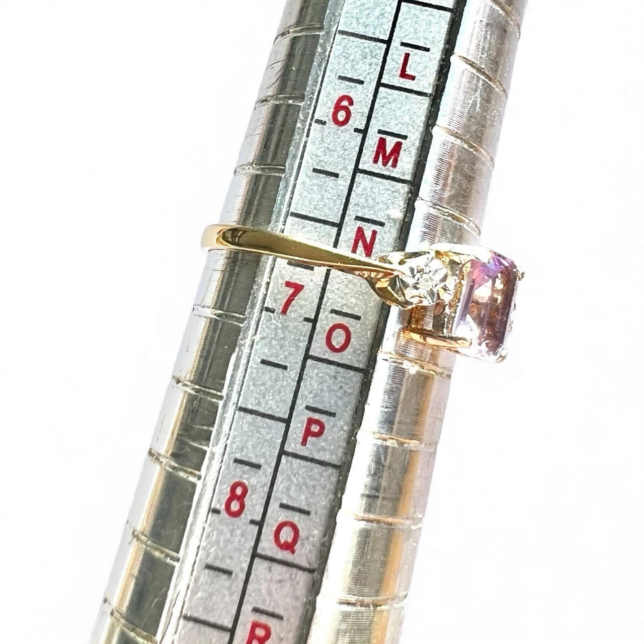 Gold ring with a gemstone on a ring sizer gauge for size reference