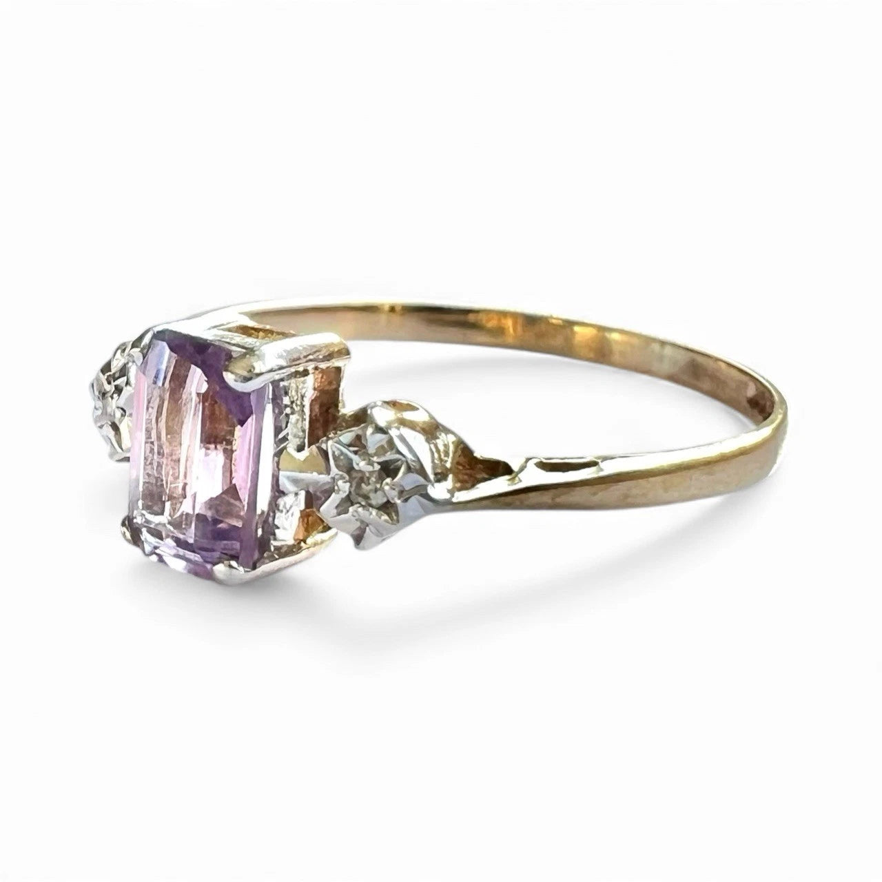 Close up Gold ring with a purple amethyst gemstone and diamonds on a white background