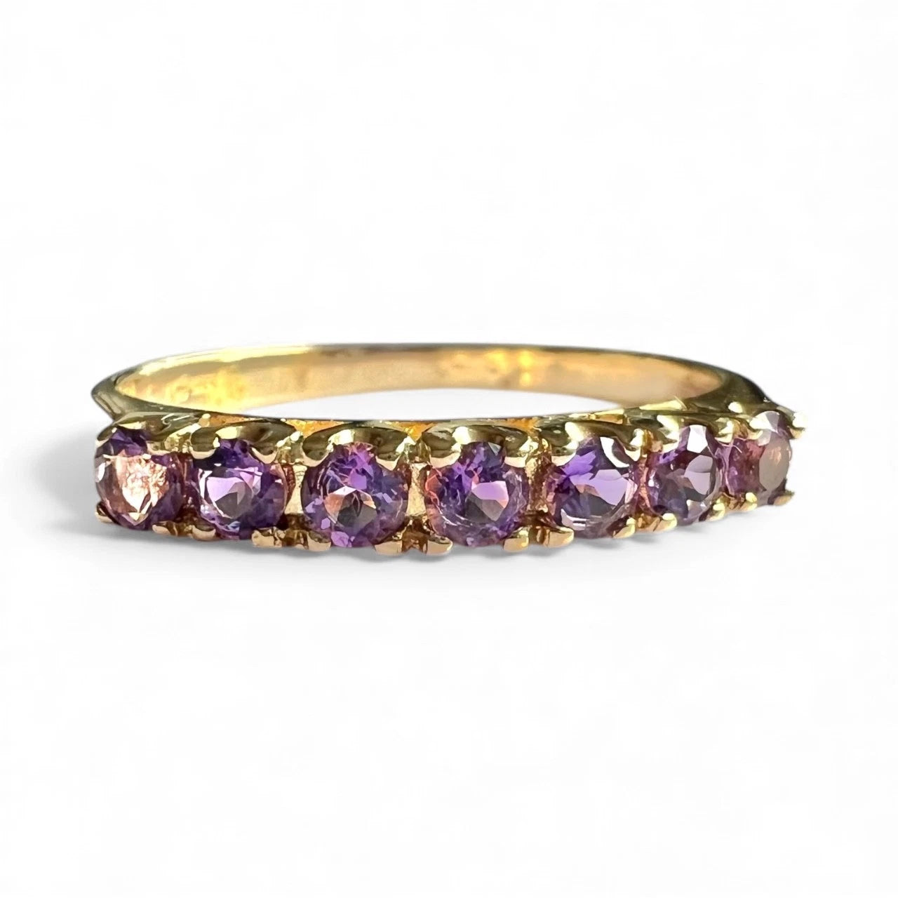 Close up Gold ring with purple amethyst gemstones on a white background