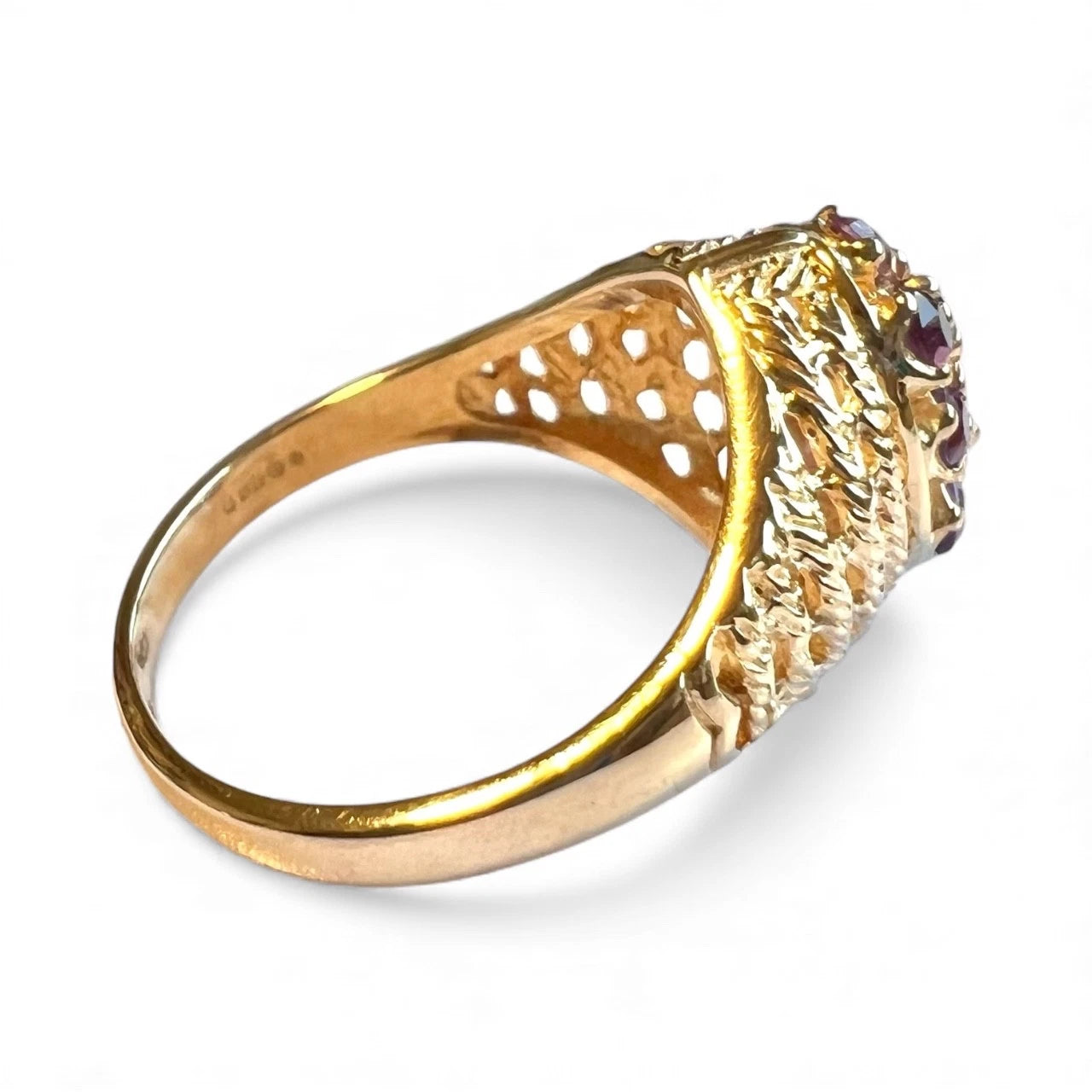 Gold ring with intricate design and embedded gemstones on a white background