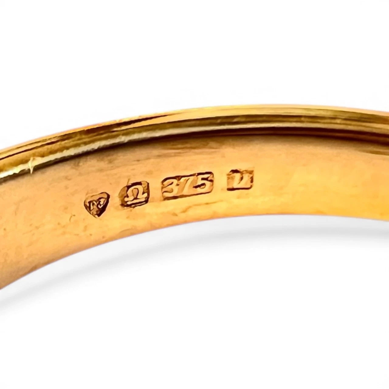 Close-up of a gold ring hallmark on a white background