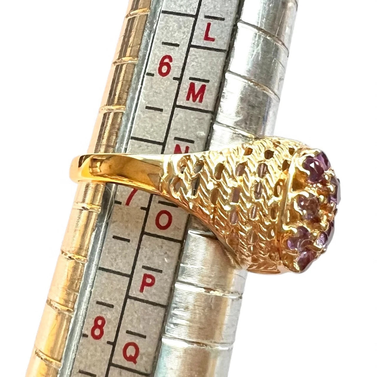 Gold ring with gemstones on a ring sizer for size reference