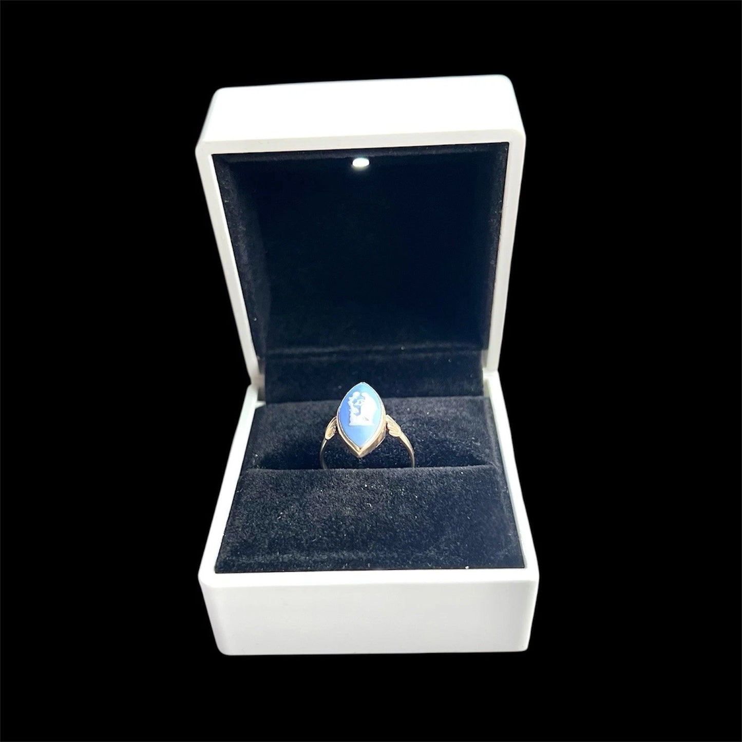 Ring with a blue marquise cameo in a white box on a black background