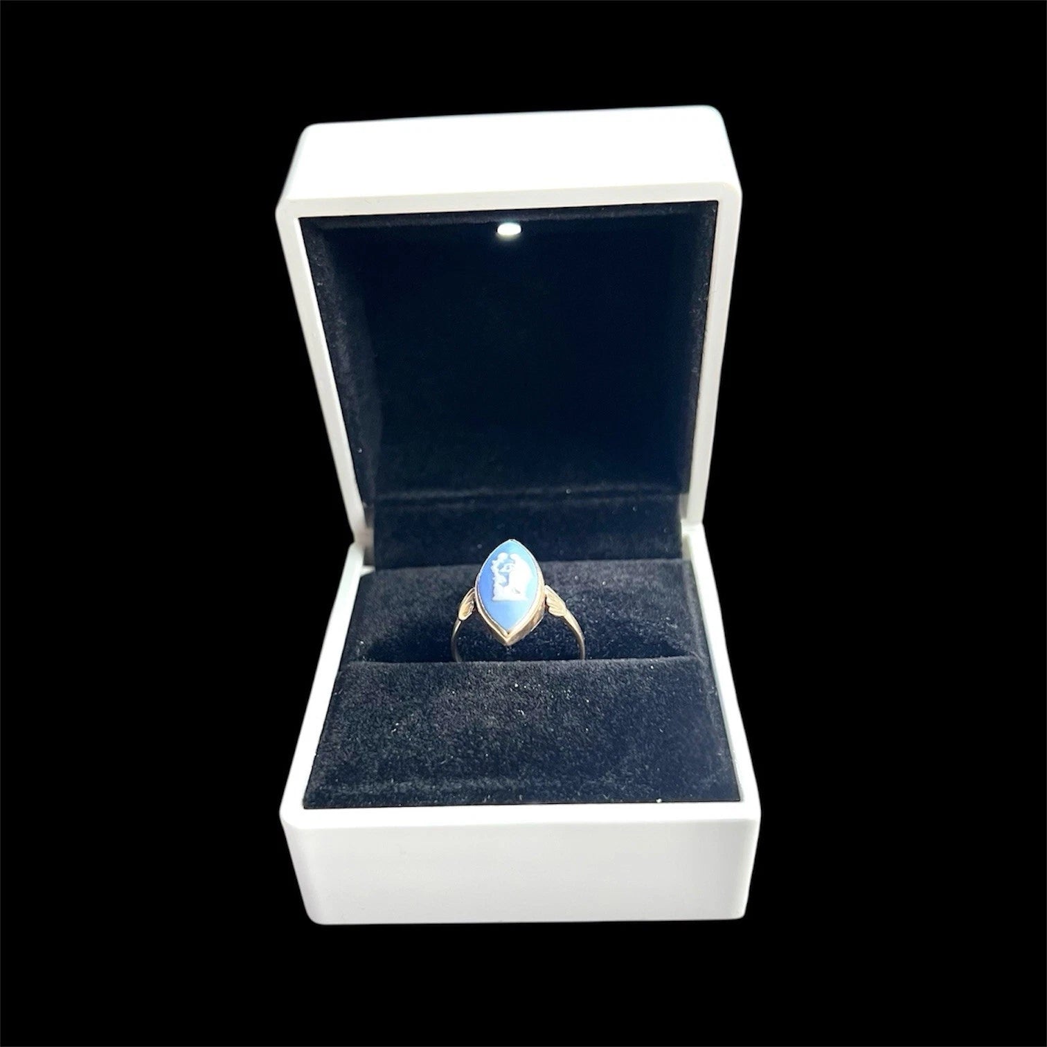 Ring with a blue marquise cameo in a white box on a black background