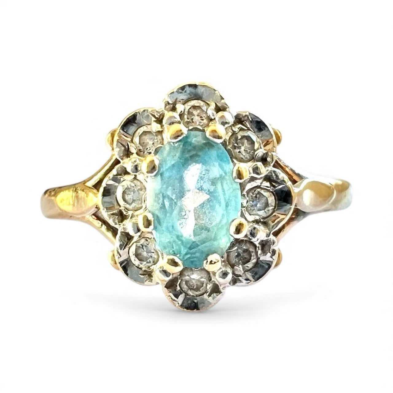Gold ring with a central blue topaz gemstone and diamond halo on a white background