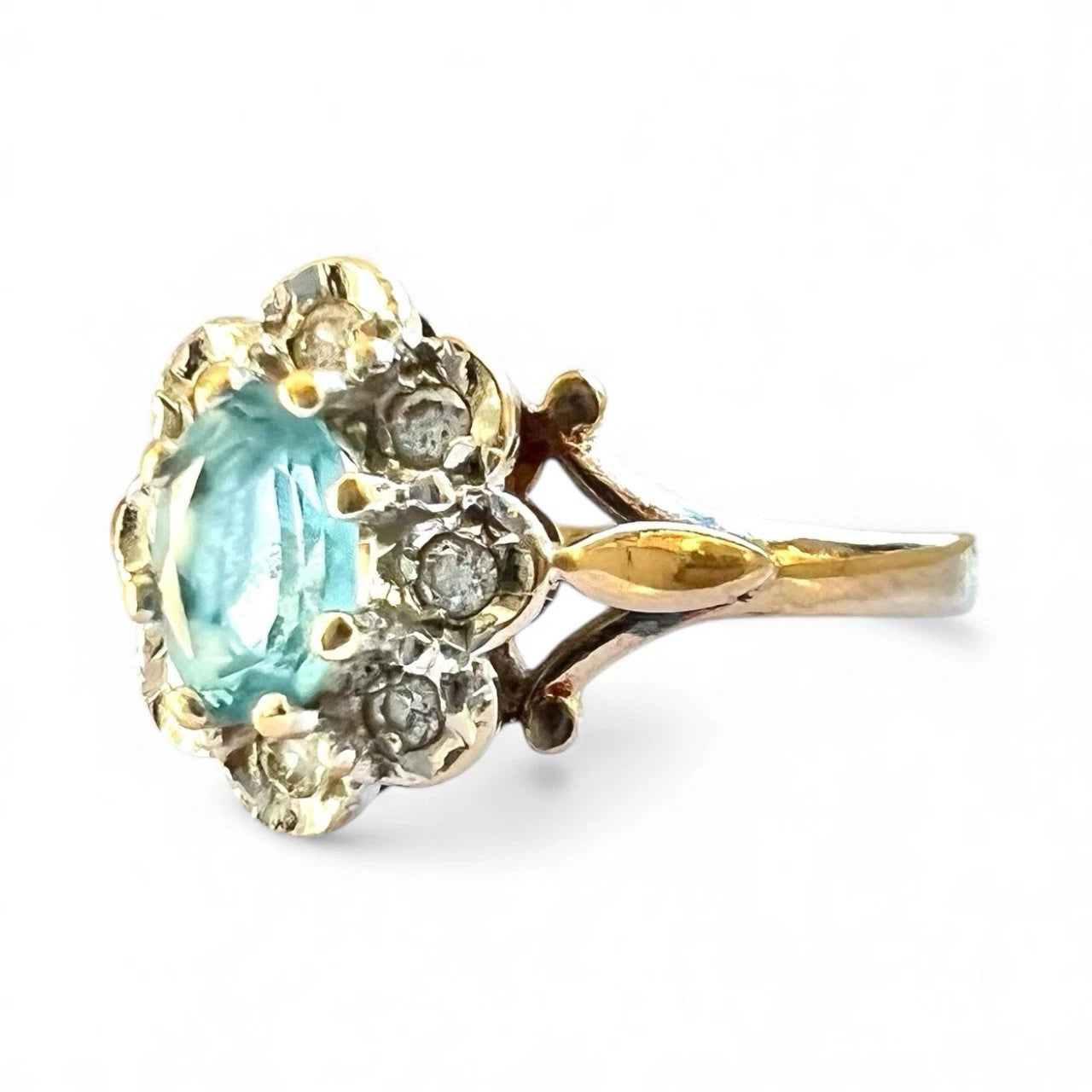 Gold ring with a central blue topaz gemstone and smaller diamonds on a white background