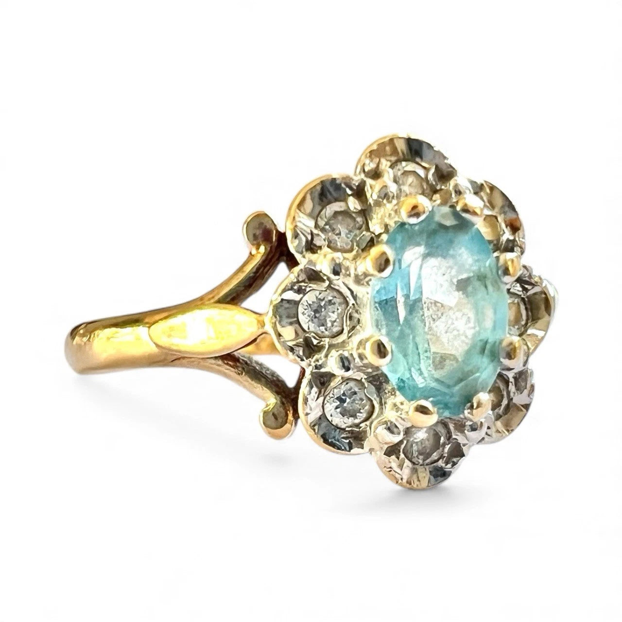 Gold ring with a blue topaz gemstone and diamond halo on a white background