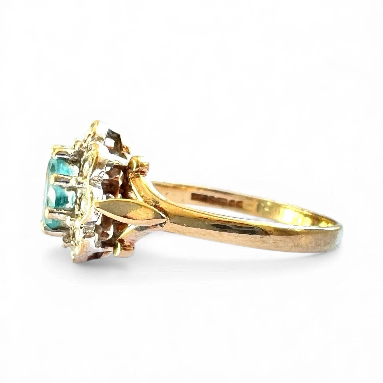 Gold ring with blue topaz gemstone and diamond halo on a white background