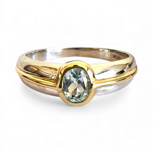Two-tone gold and white gold ring with a blue topaz gemstone on a white background