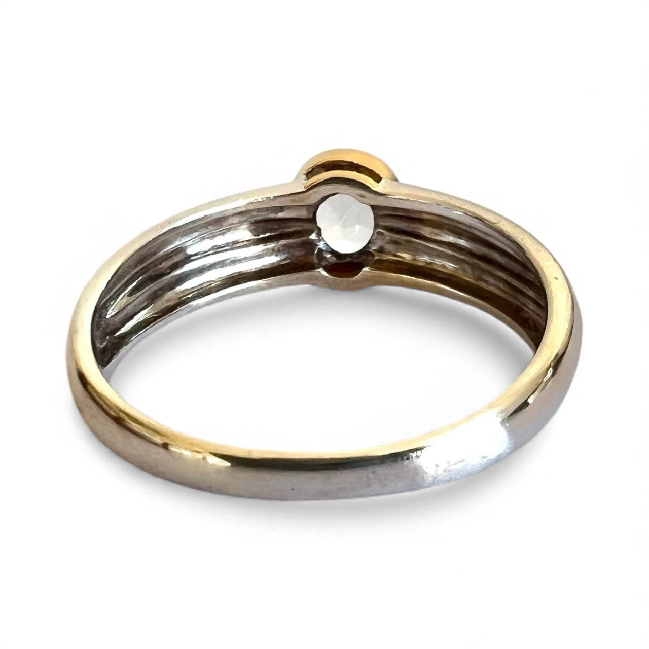 Two-tone gold and white gold ring with a small gemstone on a white background