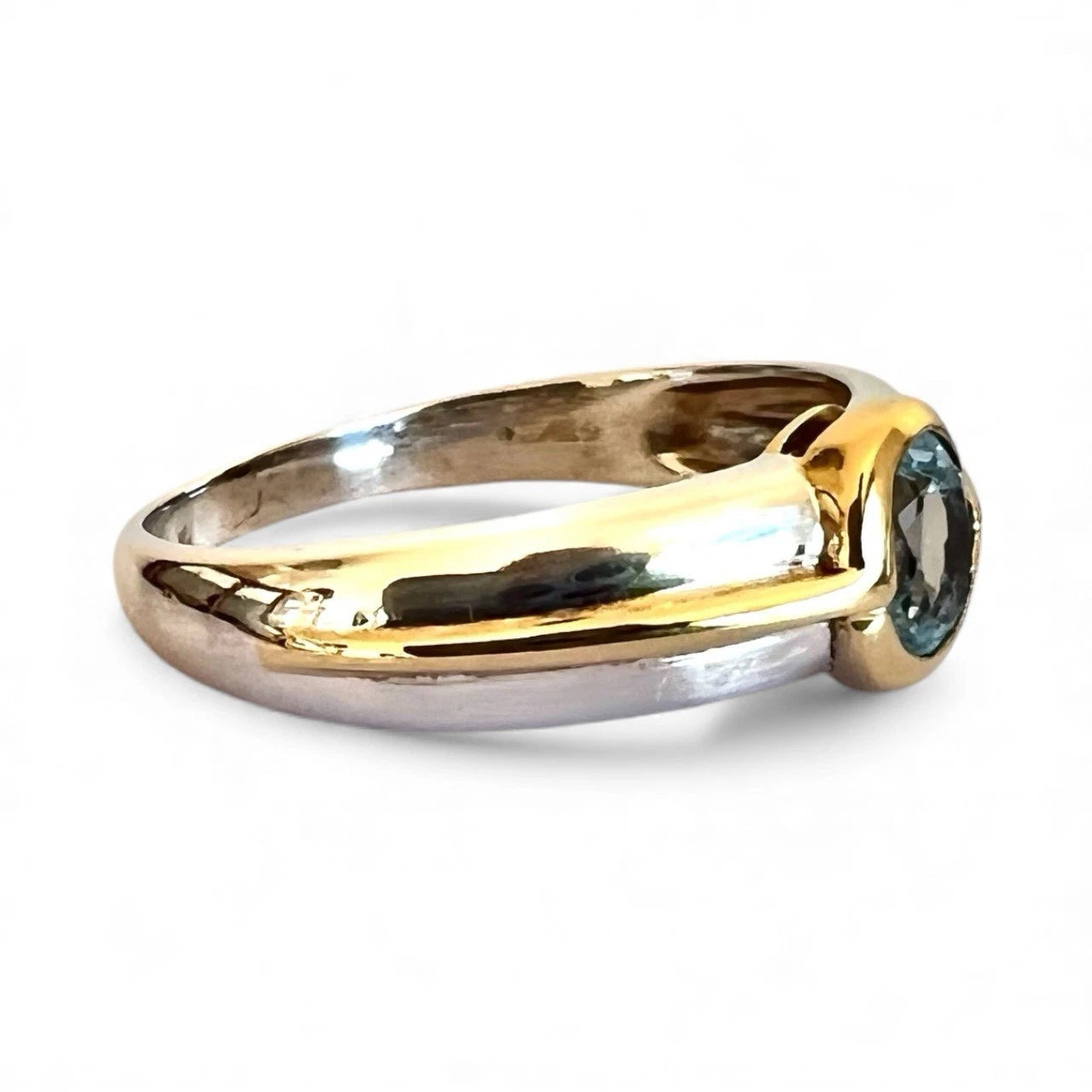 Two-tone gold and white gold ring with a blue topaz gemstone on a white background