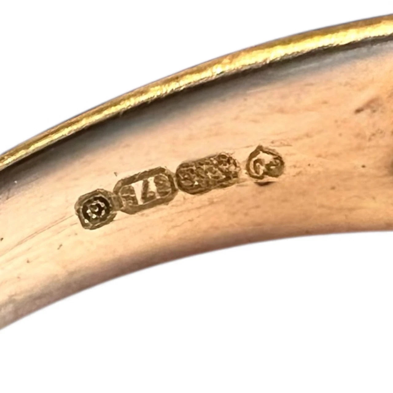 Close-up of a gold ring with visible hallmarking on a white background