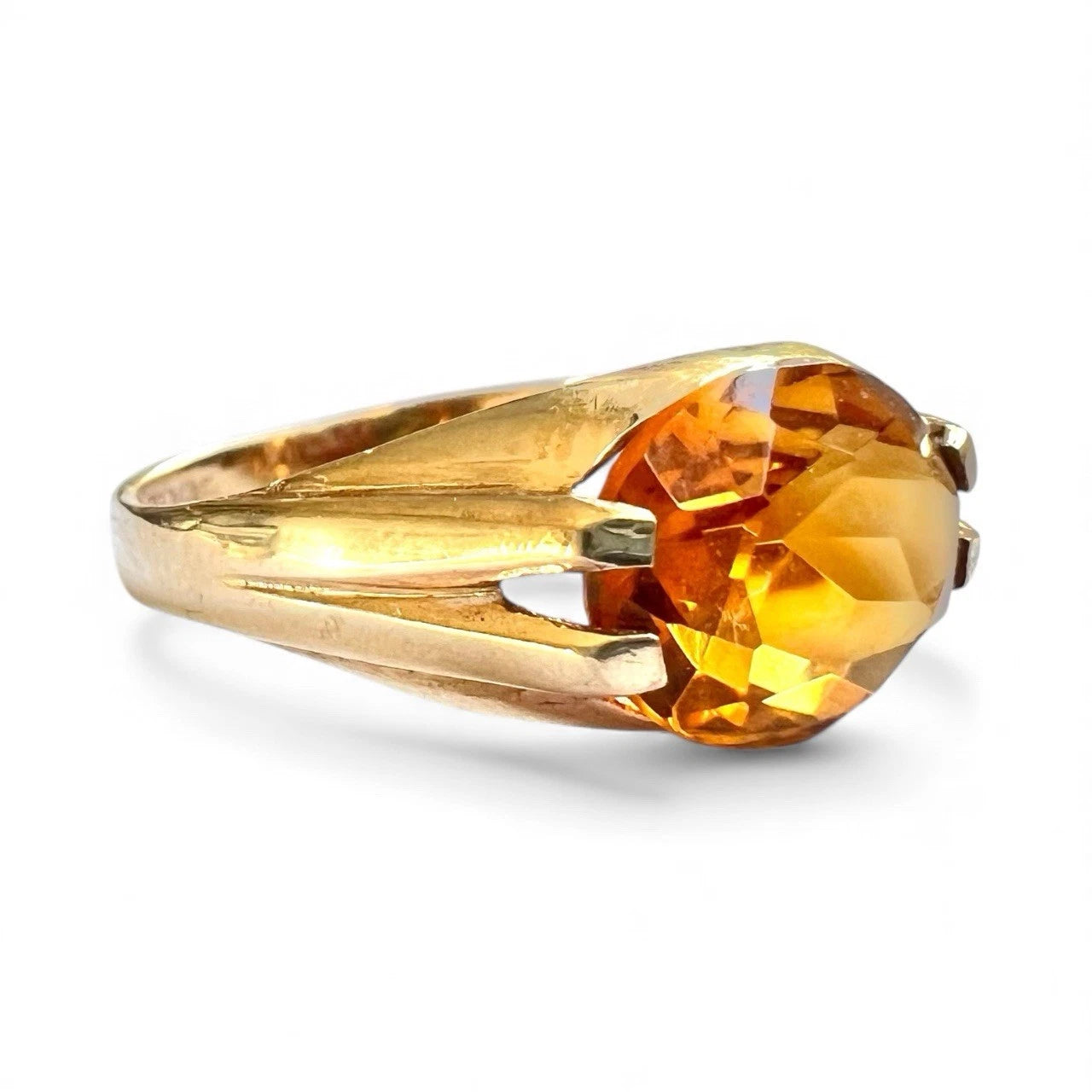 Gold ring with a large orange citrine gemstone on a white background