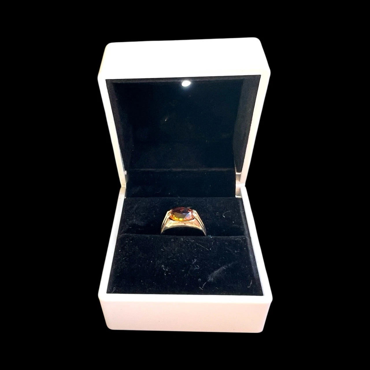 Gold ring with a citrine gemstone in an open jewellery box on a black background