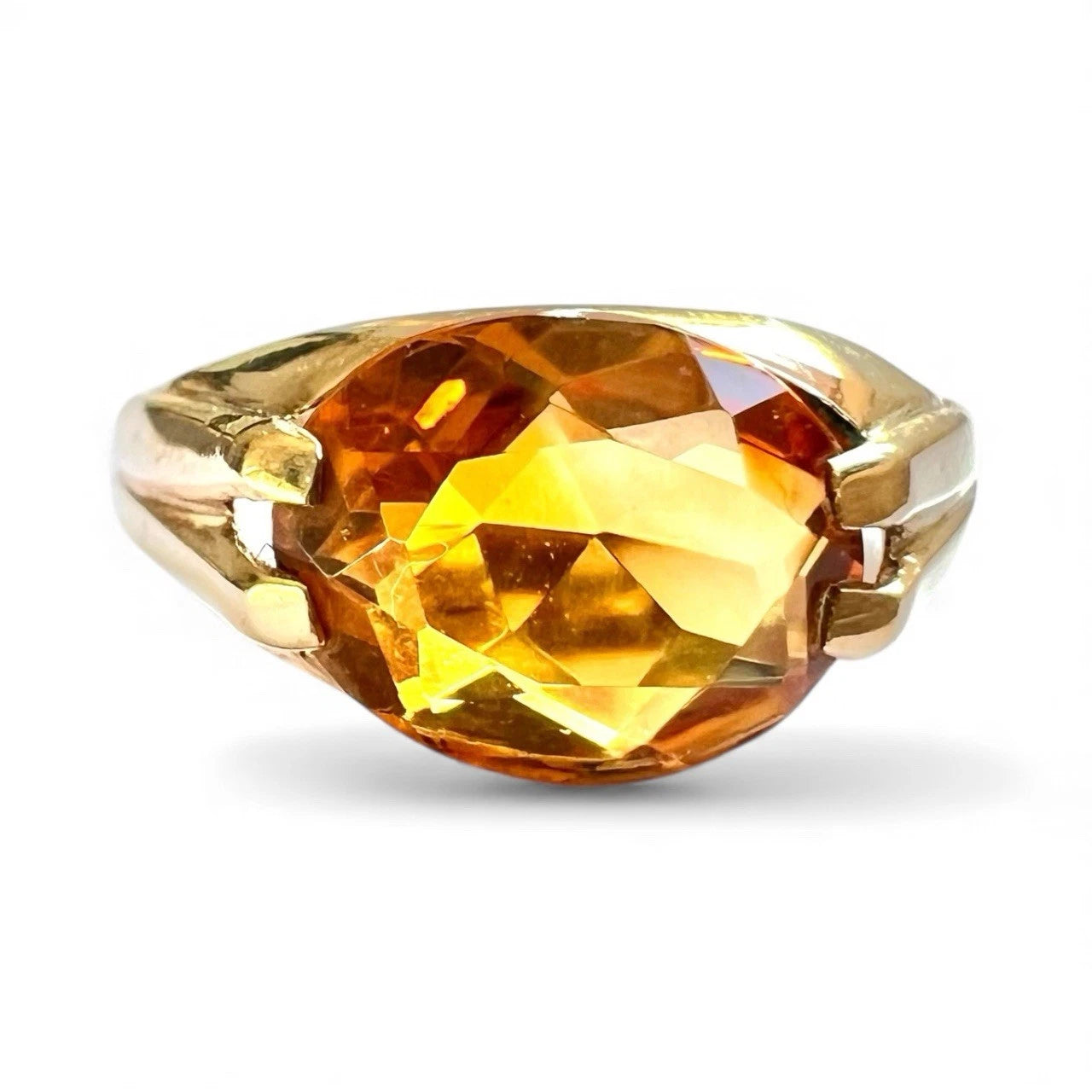 Close up gold ring with a large orange citrine gemstone on a white background