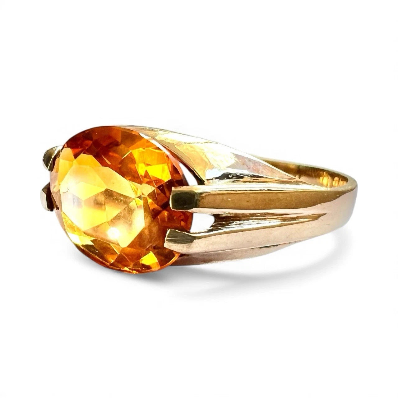 Gold ring with a large orange citrine gemstone on a white background
