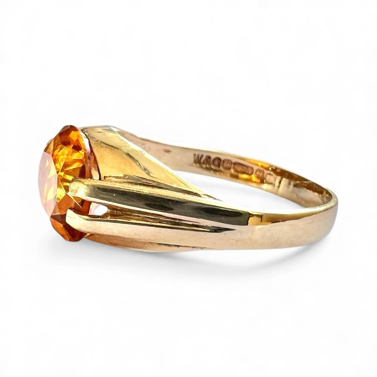 Gold ring with a large orange citrine gemstone on a white background