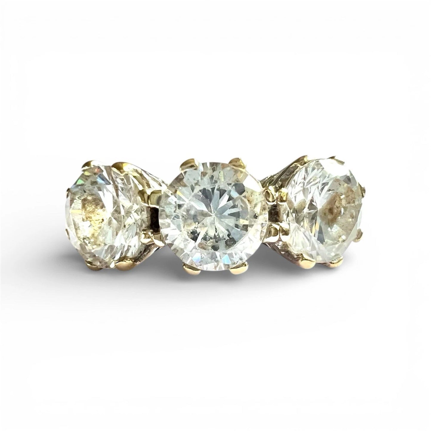 Three stone ring with gold prongs on a white background