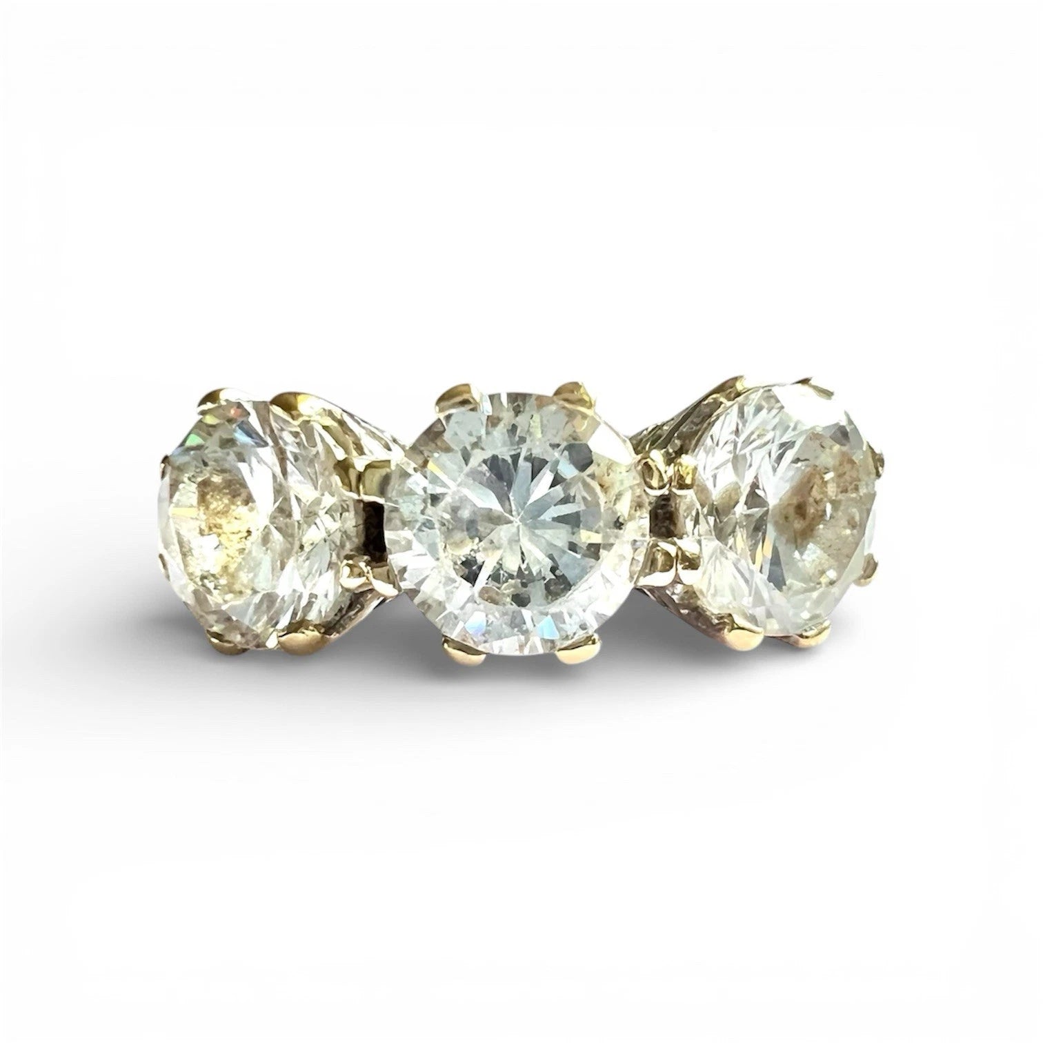 Three stone ring with gold prongs on a white background