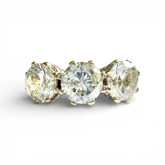 Three stone ring with gold prongs on a white background