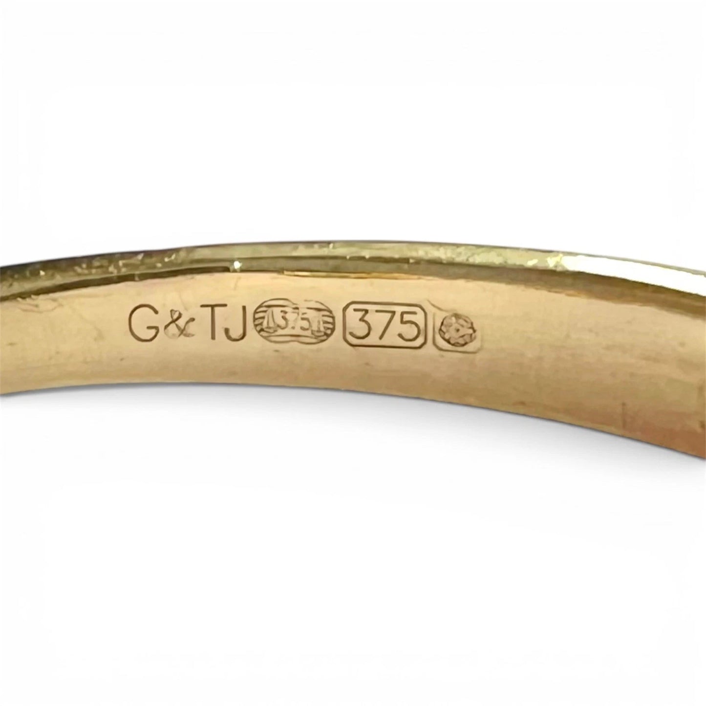 Gold ring with 'G& TJ' branding and '375' hallmark on a white background