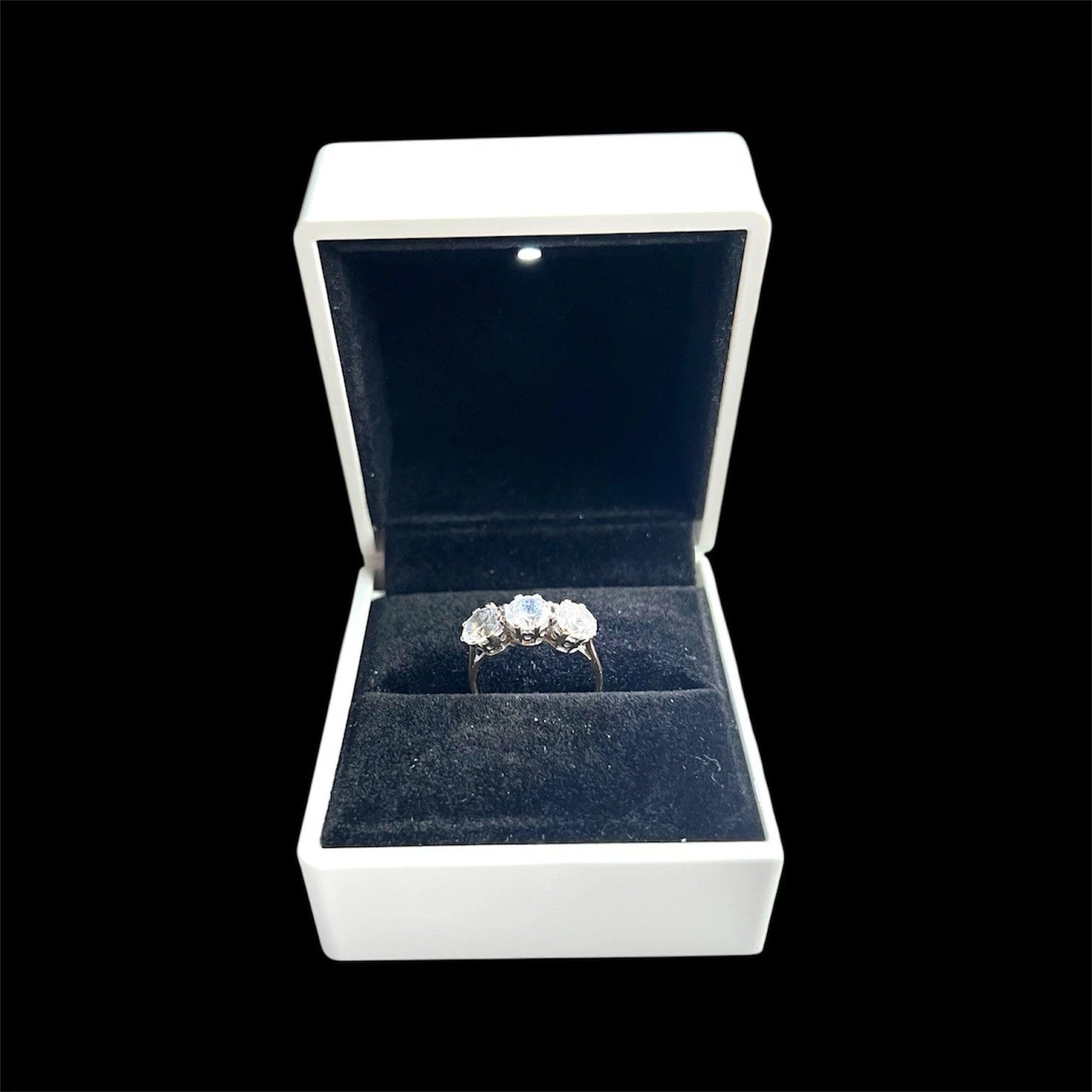 Three Stone Gold ring in a white jewellery box with a black background