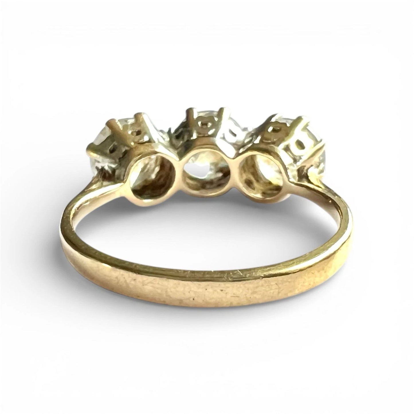 Rear view close up of gold three stone CZ ring setting on a white background