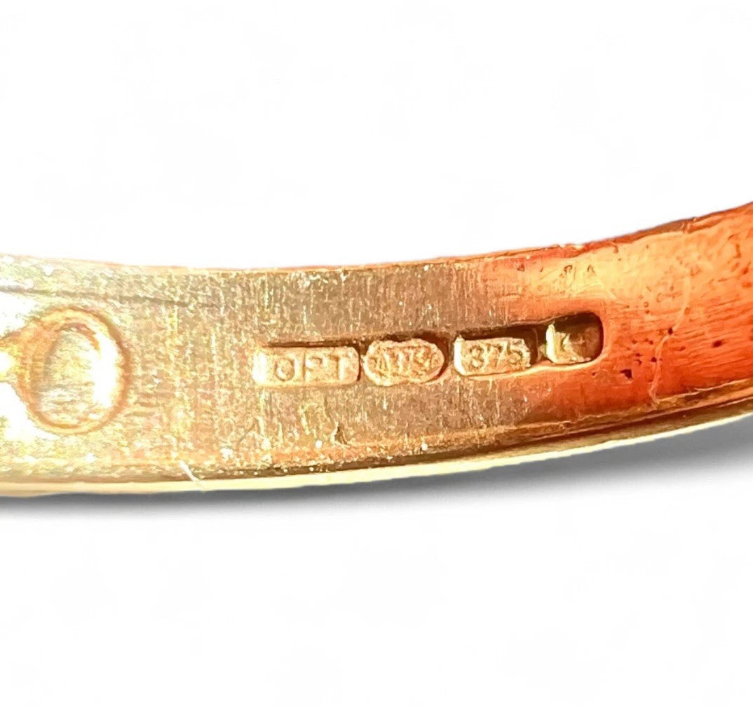 Close-up of a gold ring with visible hallmarking on a white background