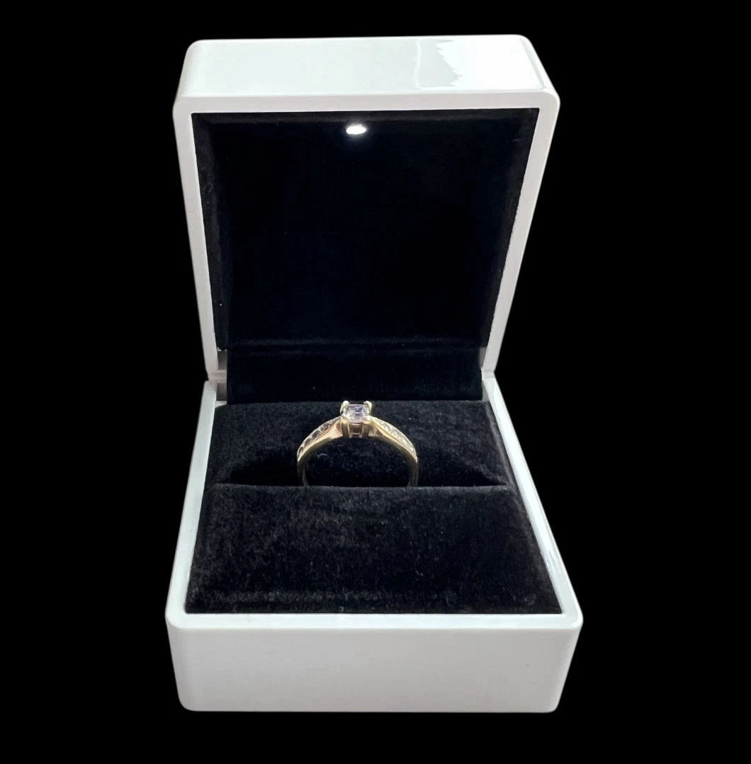 Gold ring with a cubic zirconia in a white jewellery box on a black background