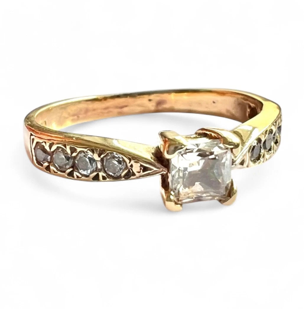 Gold ring with a large CZ and smaller CZ on a white background