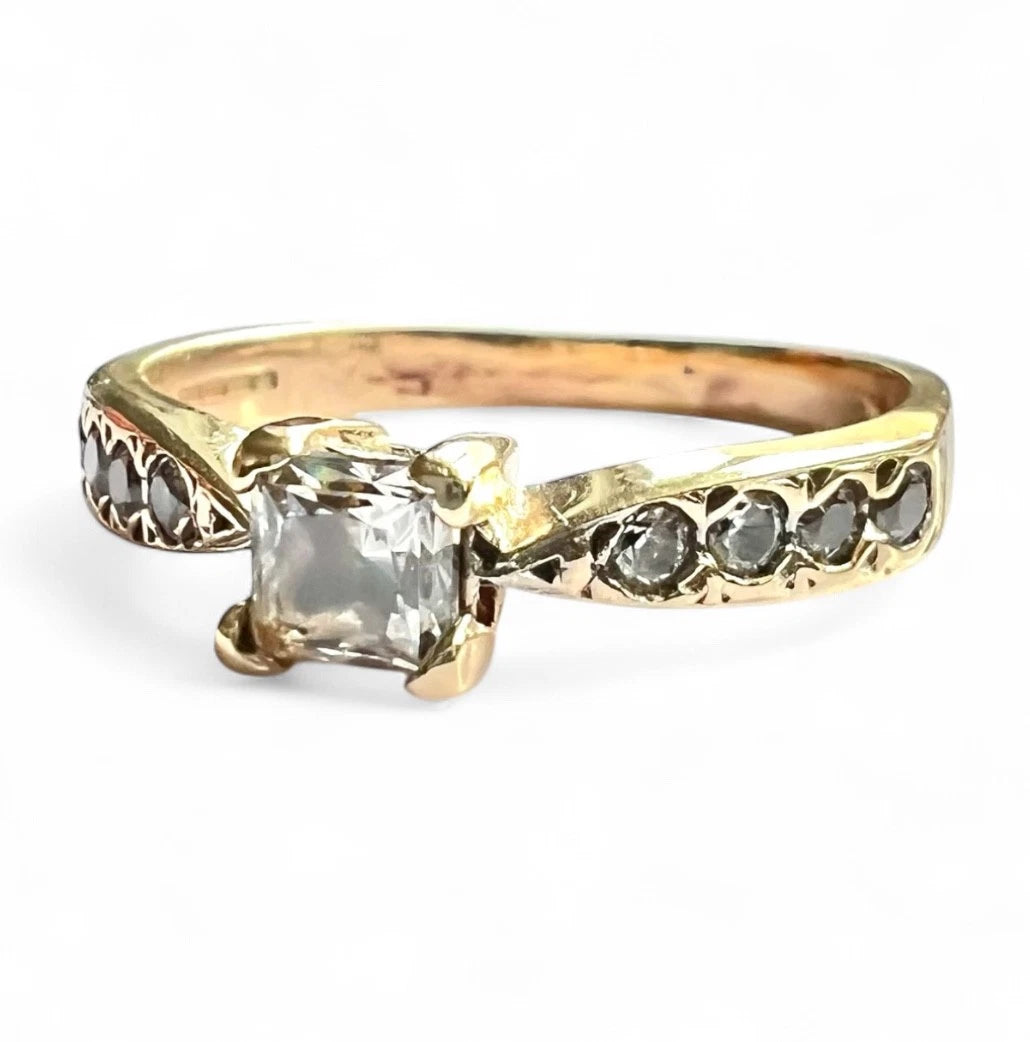 Gold ring with a large central CZ and smaller CZ on the band against a white background