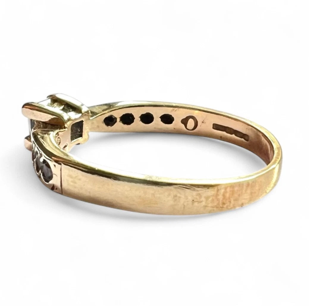 Gold ring with a CZ on a white background, close up side view of band 