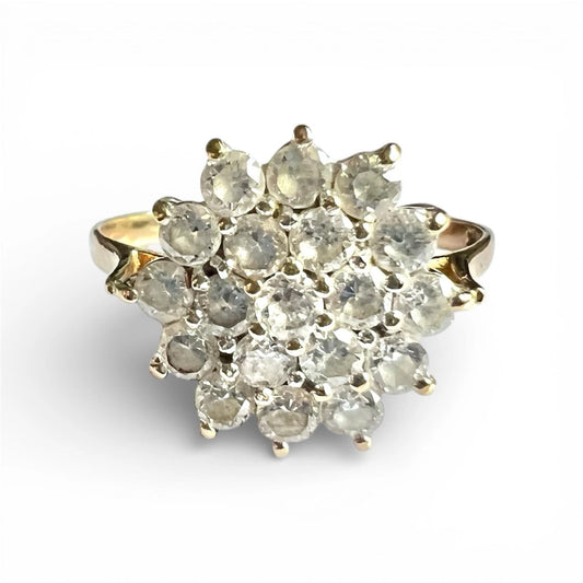 Close up gold ring with cubic zirconia gemstones cluster on a white background