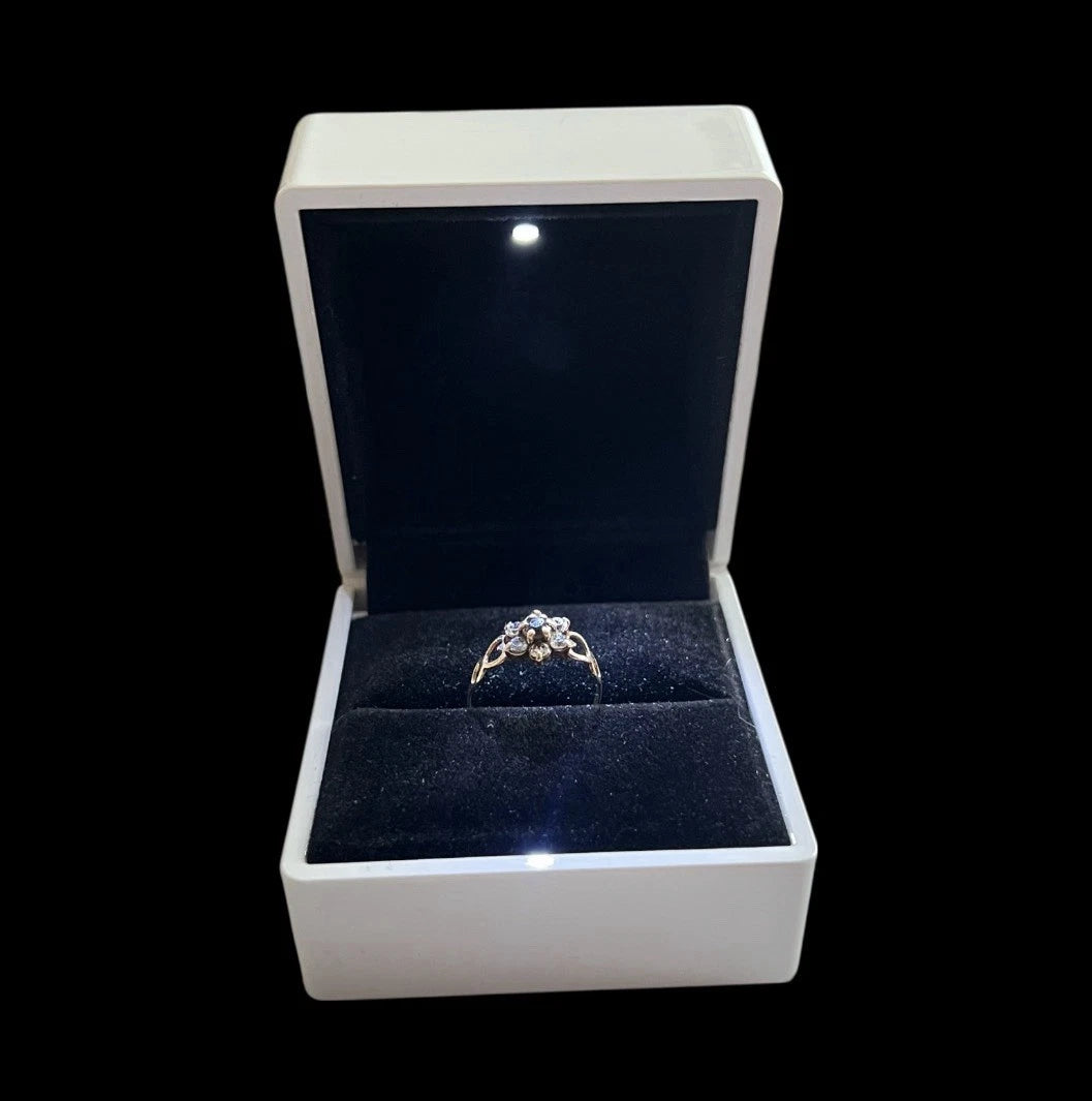 Gold Flower cluster ring in a white box with a black interior