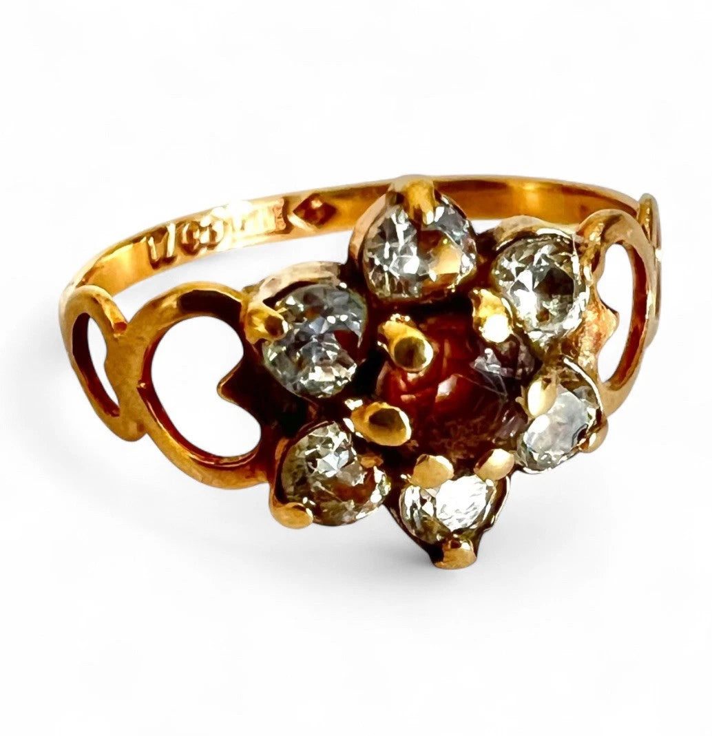 Gold ring with cubic zirconia stones in a flower setting on a white background, close up 