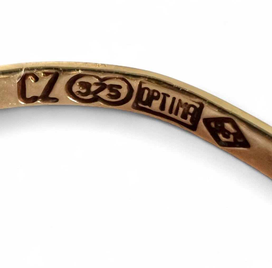 Close-up of a gold ring with engraved hallmark on a white background