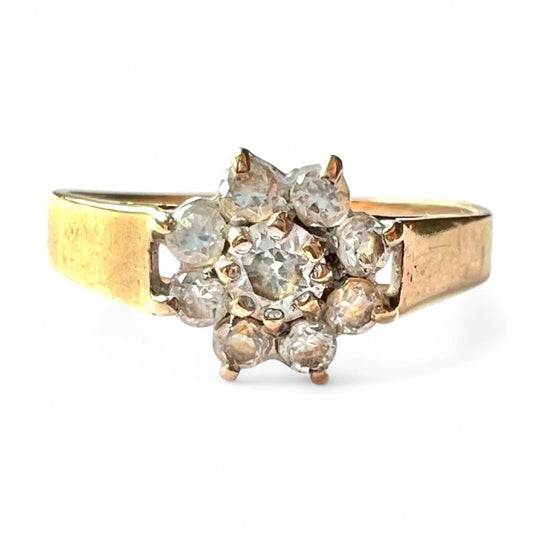 Gold ring with cubic zirconia cluster on a white background, close up front view of setting 