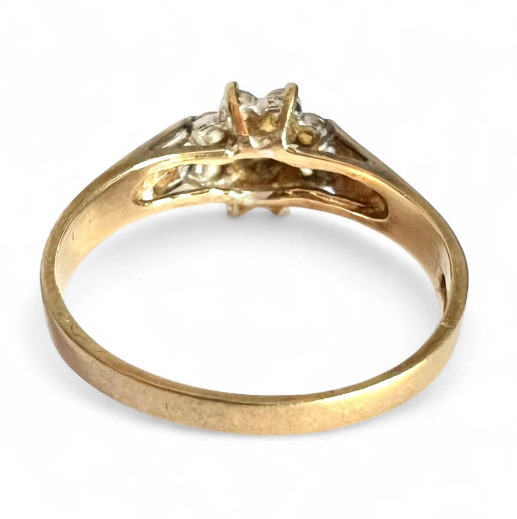 Gold cluster ring with cubic zirconia on a white background, close up rear view of setting and gold band 