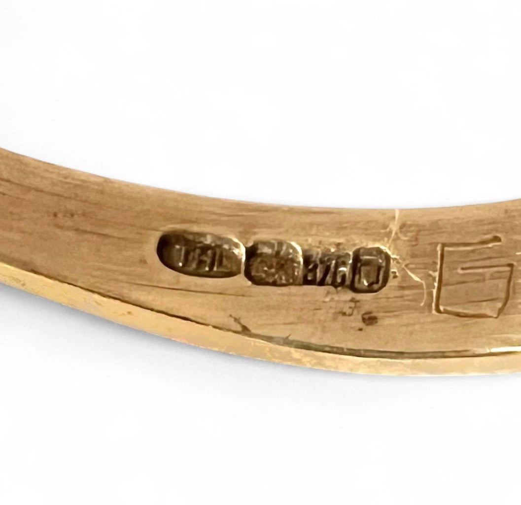 Close-up of a gold ring with visible hallmarking on a white background