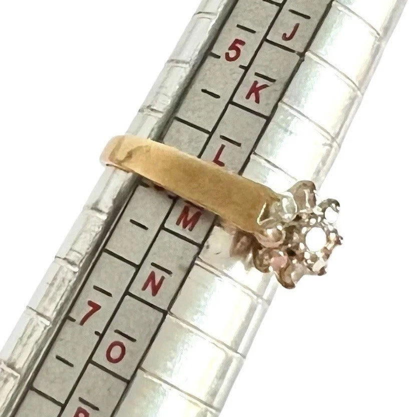 Gold ring with a cubic zirconia cluster on a metal ruler