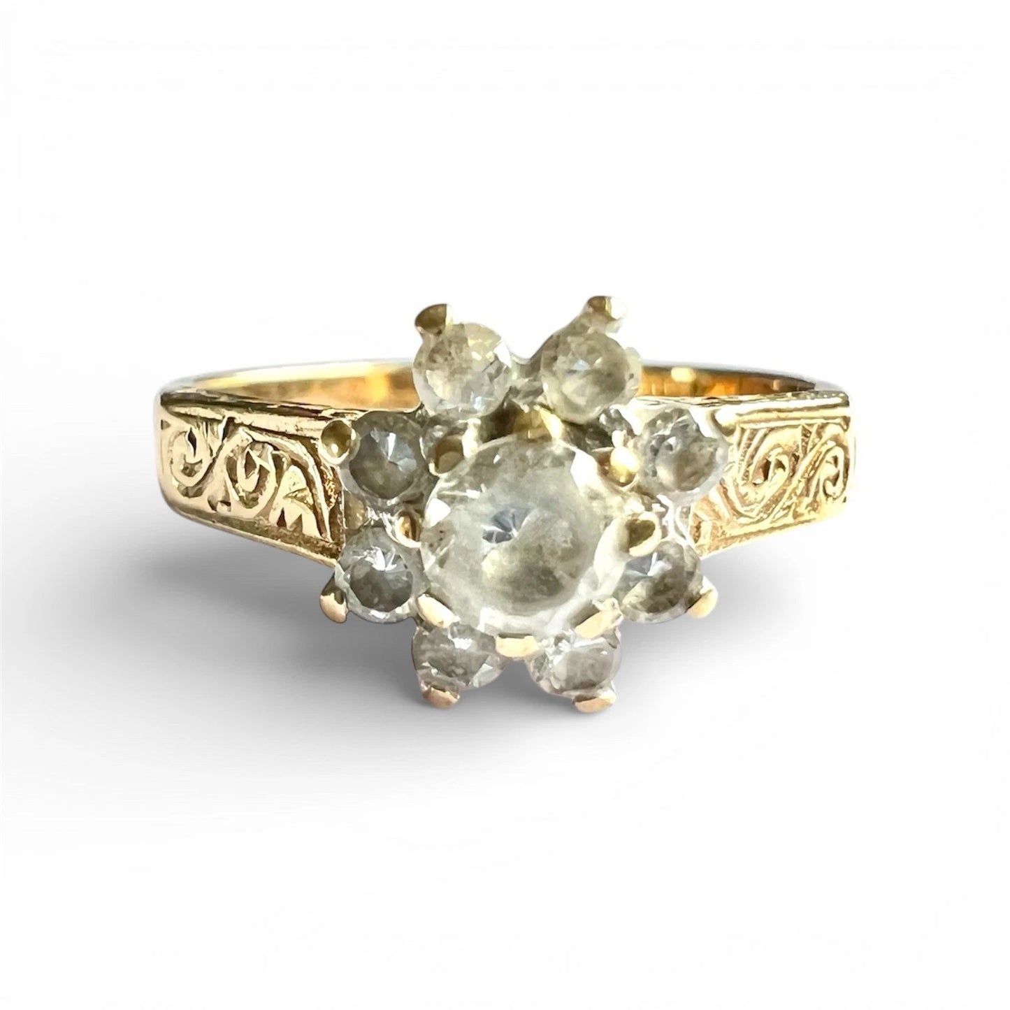Gold ring with decorative band and central gemstone on a white background