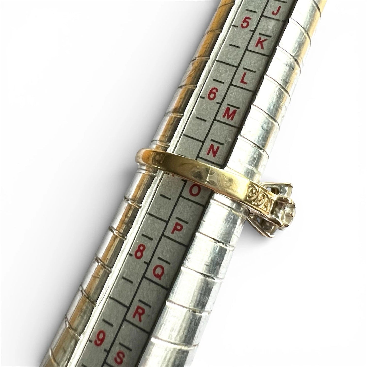 Close-up of a ring on a metallic ring sizer gauge with  on a white background