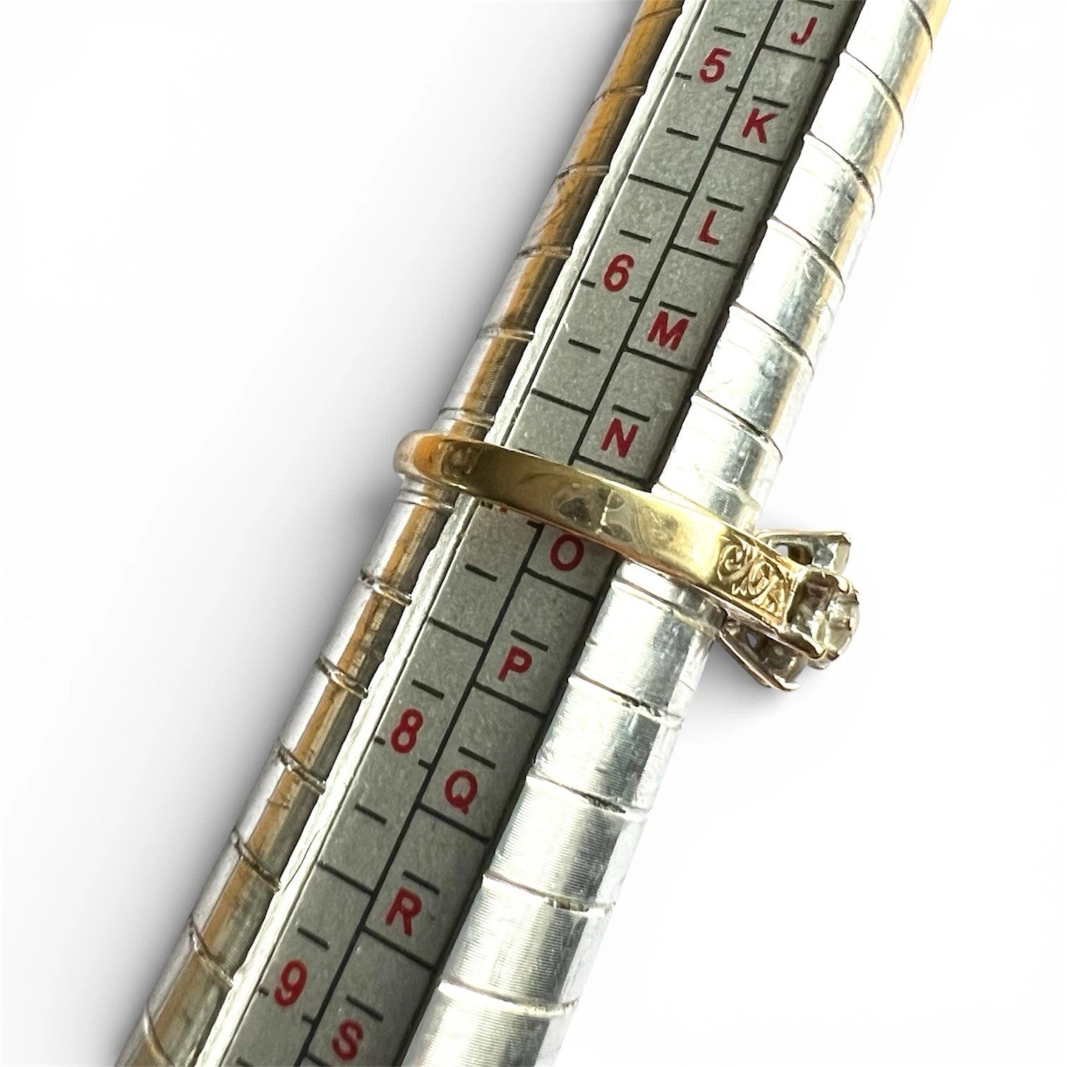 Close-up of a ring on a metallic ring sizer gauge with  on a white background
