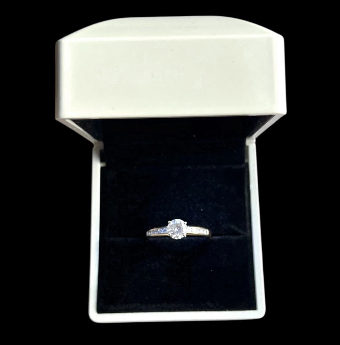 Gold Solitaire ring in a white box with black interior